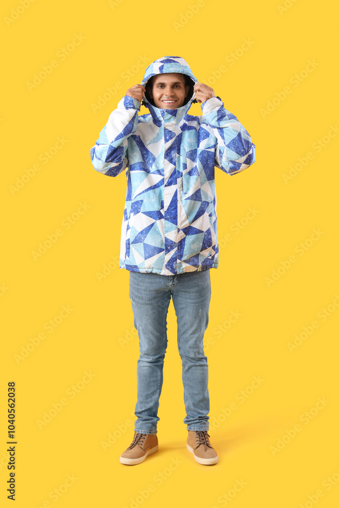 Young man in warm jacket on yellow background Young man in warm jacket on yellow background