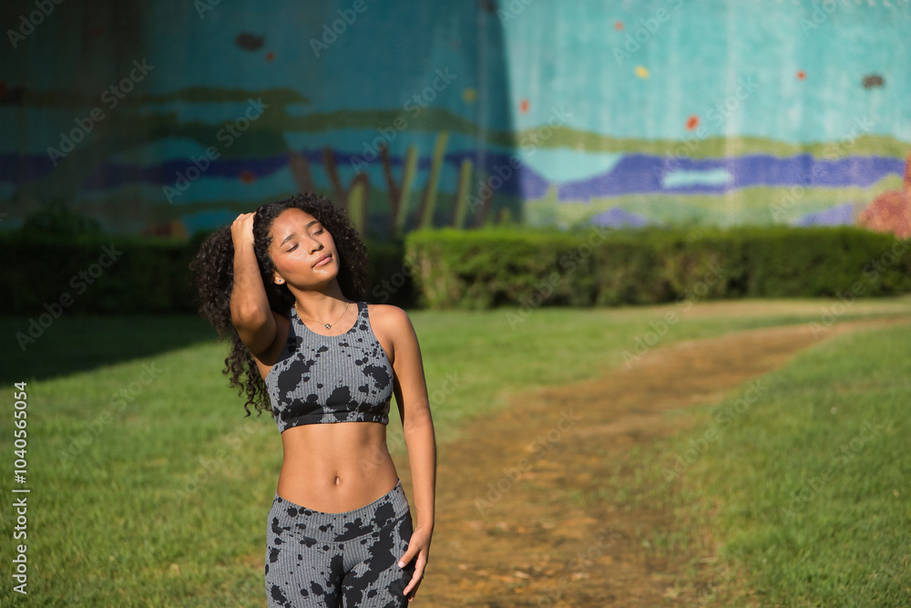 Fototapeta premium Latina woman, young, beautiful, brunette, with curly hair and sport clothes, with her hand on her head, tired and very hot after having completed her exercise routine. Concept sport, exercise, running
