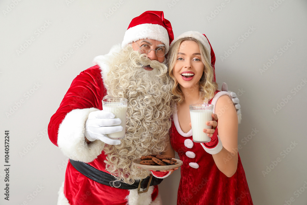 Santa Claus and beautiful woman with glasses of milk and cookies on white background Santa Claus and beautiful woman with glasses of milk and cookies on white background