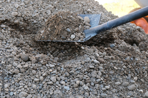 Fotografie Shovel with sand and gravel mixture on background of pile, bulk building materia
