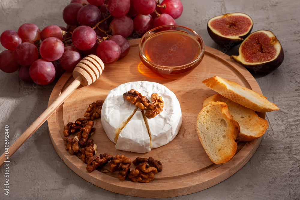 Autumn still life with ripe figs, sliced, brie or camembert cheese, grapes, walnuts, honey on a wooden chopping board. Healthy snacks. Autumn still life with ripe figs, sliced, brie or camembert cheese, grapes, walnuts, honey on a wooden chopping board. Healthy snacks.