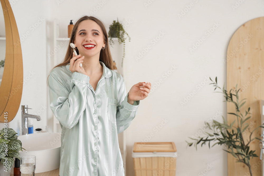 Young woman massaging her face with tool in bathroom Young woman massaging her face with tool in bathroom