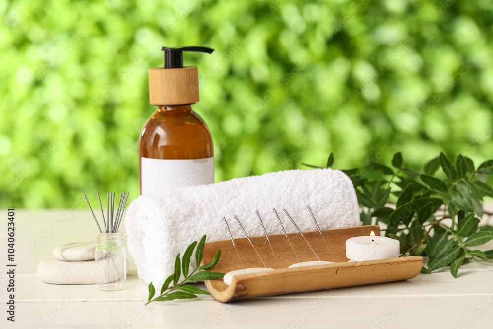 Acupuncture needles, candles, oil, towel and spa stones on table outdoors Acupuncture needles, candles, oil, towel and spa stones on table outdoors