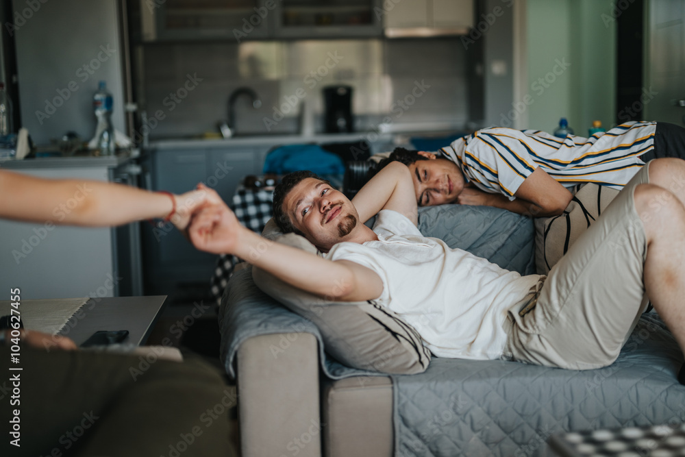 Obraz premium A group of friends enjoying a relaxed afternoon in a modern living room, showcasing friendship and leisure. One person reclines on the sofa while interacting with a friend.