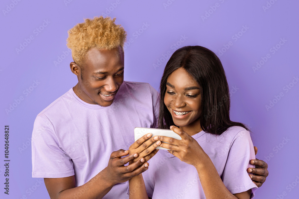 Cheerful African American lady and guy chatting on mobile phone together, violet background Cheerful African American lady and guy chatting on mobile phone together, violet background