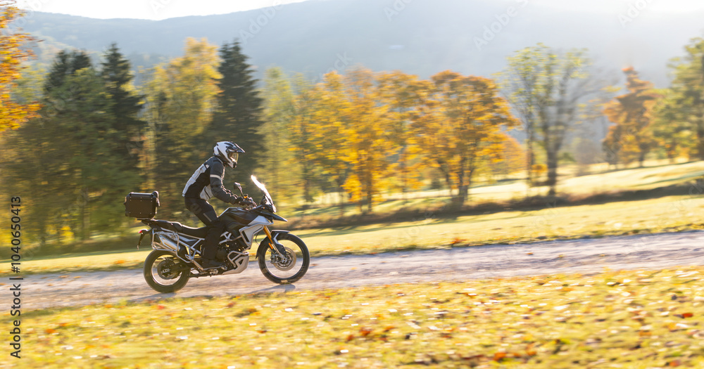 Driver riding motorcycle on empty road during sunset, autumn mountains Driver riding motorcycle on empty road during sunset, autumn mountains