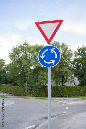 Give way road sign and roundabout. The road sign is installed in front of a roundabout.