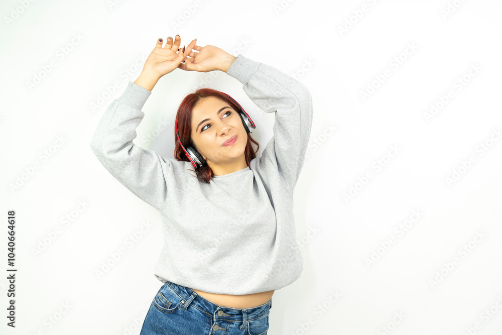 Beautiful young woman wearing stylish casual outfit isolated over white background, wearing white wireless headphones listening to music and using it Beautiful young woman wearing stylish casual outfit isolated over white background, wearing white wireless headphones listening to music and using it