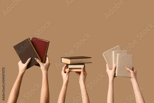 Hands holding many books on beige background