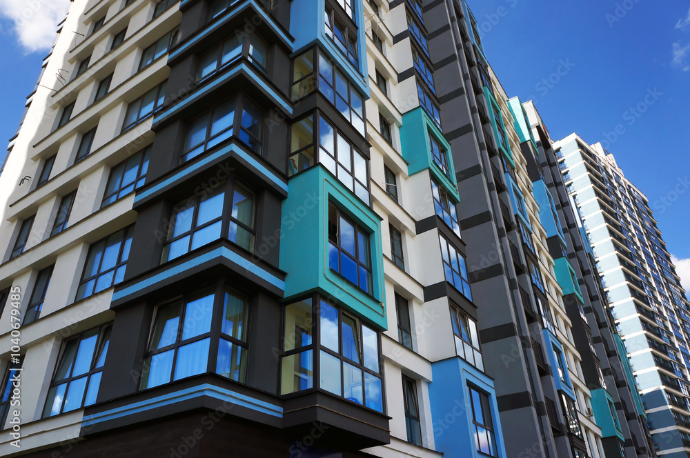 Fototapeta premium Windows on Facade of Modern Multistorey Residential Building. Corner of the House. Reflections of Blue Sky in Windows Glass. Architectural Details. 