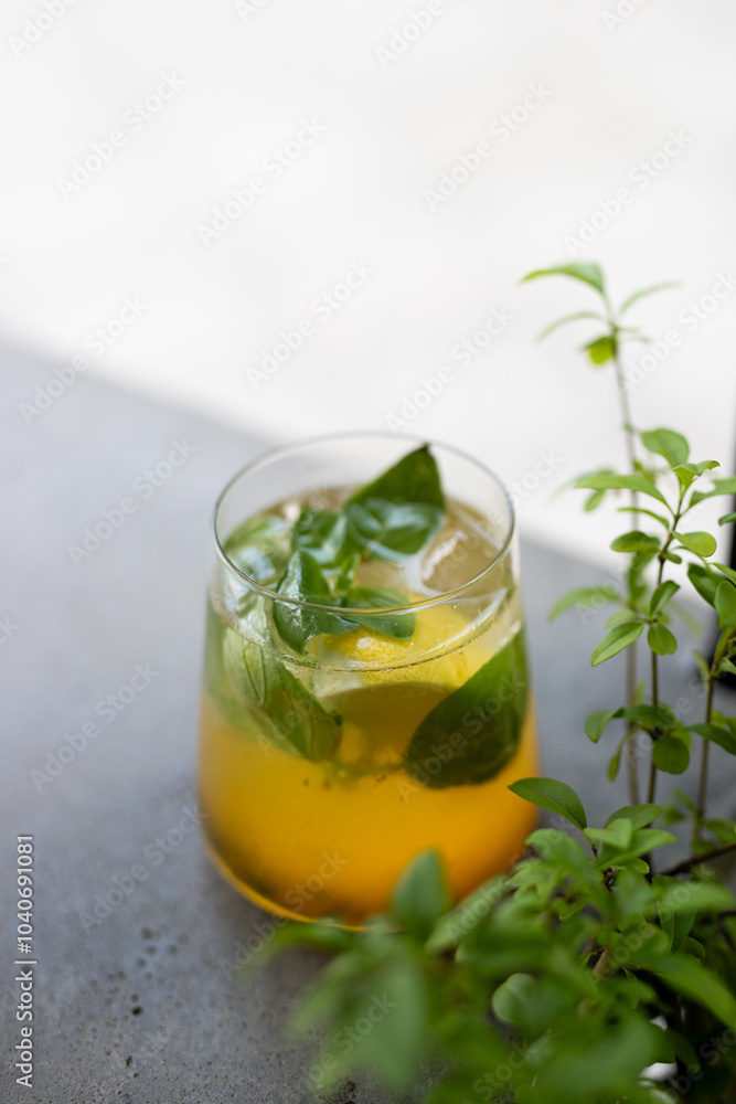 Refreshing herbal drink with mint leaves and citrus served in a clear glass on a stone countertop Refreshing herbal drink with mint leaves and citrus served in a clear glass on a stone countertop