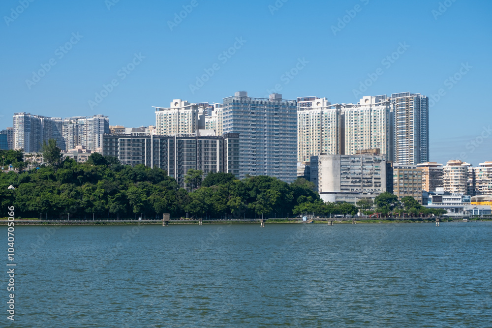 Modern high-rise residential buildings line the waterfront in Macao, China. A lush green park buffer stretches along the shoreline. Parque de Reservatório Modern high-rise residential buildings line the waterfront in Macao, China. A lush green park buffer stretches along the shoreline. Parque de Reservatório