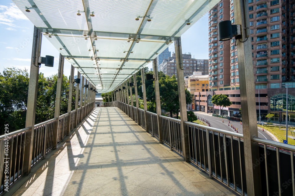 A covered pedestrian bridge or walkway with metal railing and a glass roof that provides shelter from the weather, allowing natural light. A protected and convenient route for pedestrians. Macau China A covered pedestrian bridge or walkway with metal railing and a glass roof that provides shelter from the weather, allowing natural light. A protected and convenient route for pedestrians. Macau China