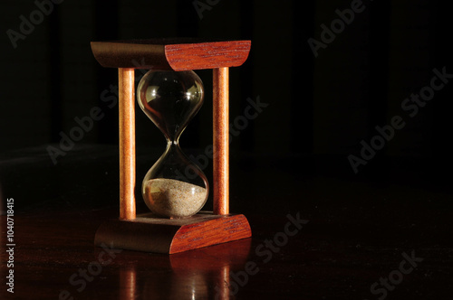 Hourglass with wooden frame on dark background symbolizing time passage