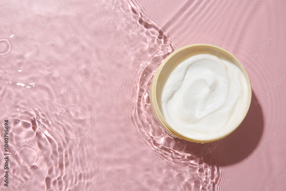 Cosmetic product. Jar with cream in water on pink background, top view. Space for text Cosmetic product. Jar with cream in water on pink background, top view. Space for text