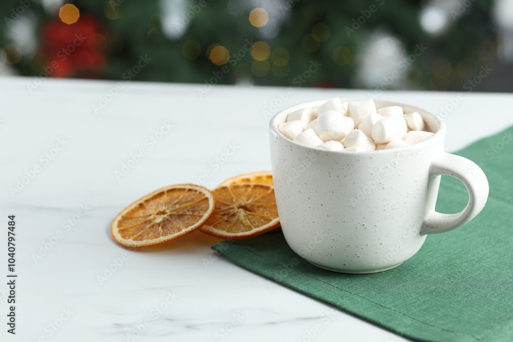 Tasty hot cocoa drink with marshmallows in cup and dry orange slices on white table, closeup. Space for text Tasty hot cocoa drink with marshmallows in cup and dry orange slices on white table, closeup. Space for text