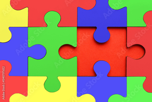 Many colorful puzzle pieces on red background, top view. Symbol of autism