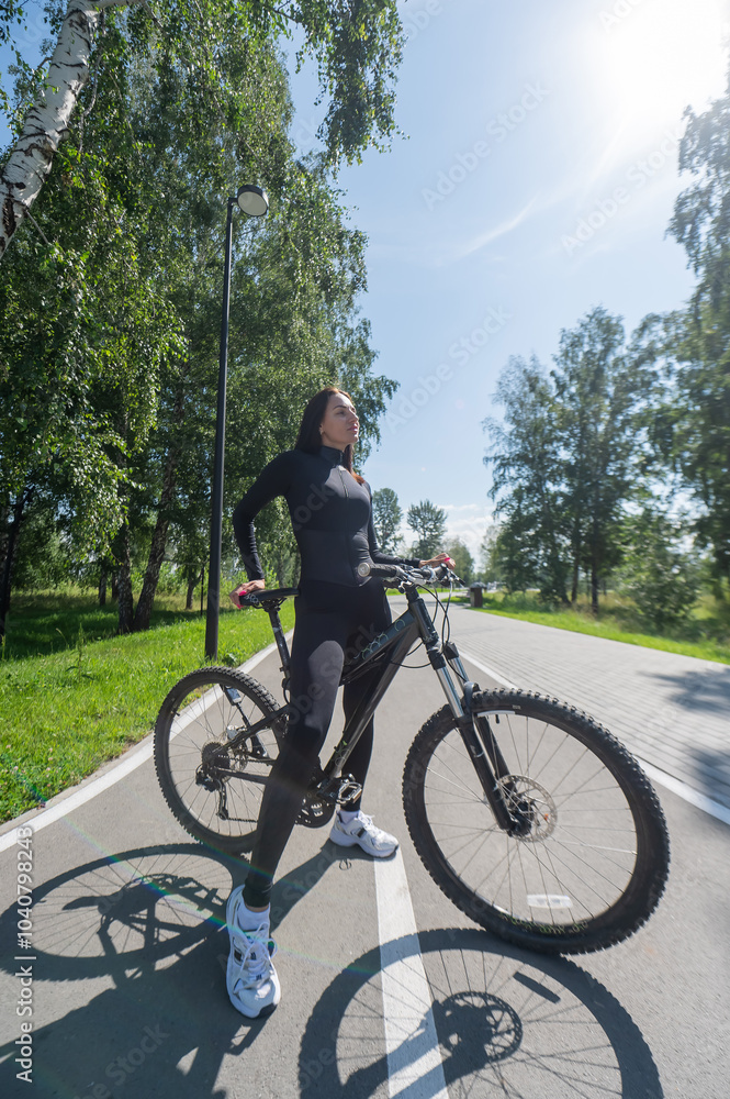 Caucasian woman riding a bike in a park. Vertical photo. 