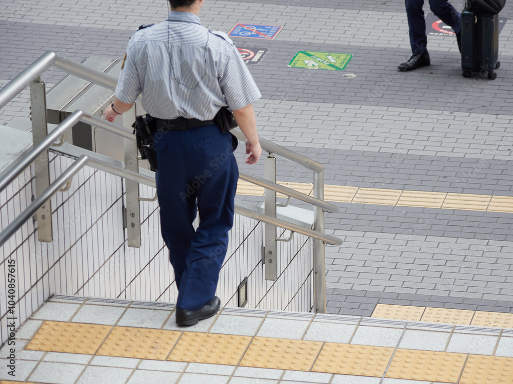 昼の都市の繁華街で巡査している男性警備員の姿 昼の都市の繁華街で巡査している男性警備員の姿