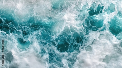 Overhead view of turquoise ocean water with white foamy waves.