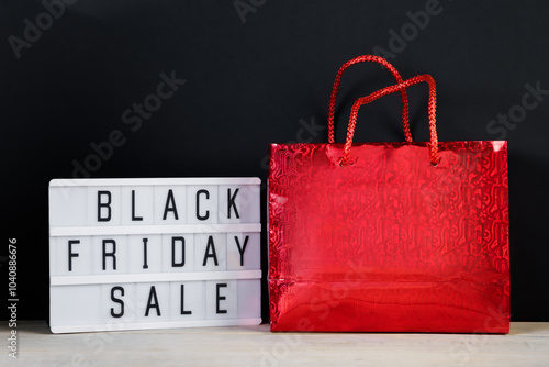 Black Friday sale. Red shopping bag and lightbox on dark background.