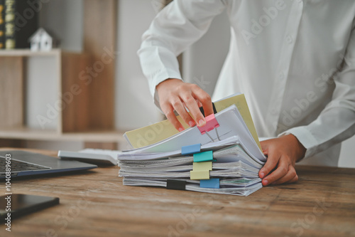 A person is sorting through a stack of papers on a desk