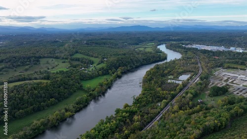 Aerial establishing shot of river surrounded by green american nature during sunrise in autumn. Wide shot. photo