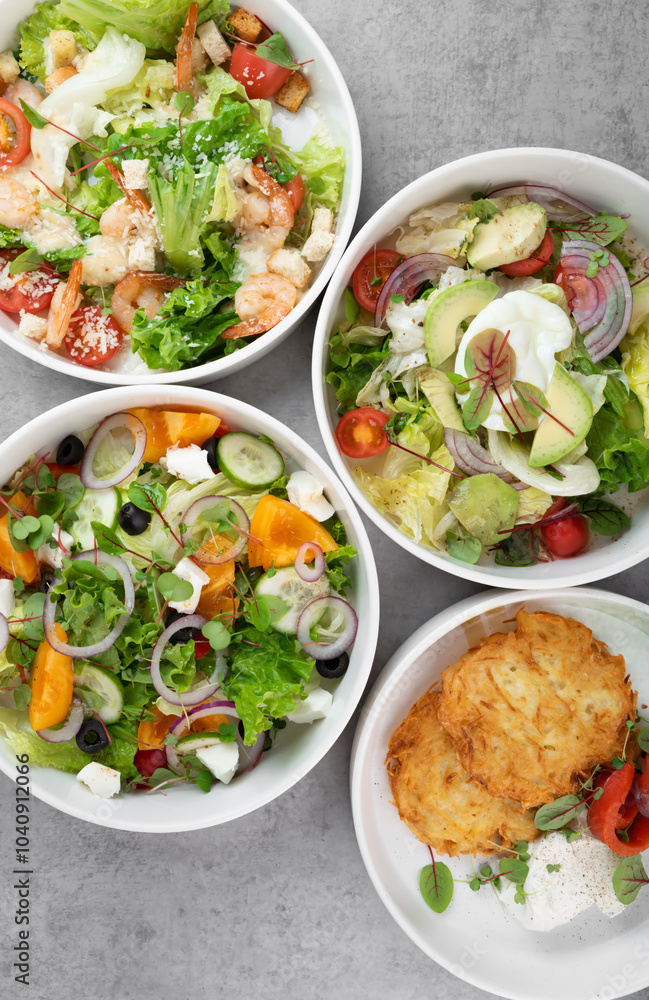 Three different vegetable salads and slavic draniki (potato pancakes) on gray marble background Three different vegetable salads and slavic draniki (potato pancakes) on gray marble background