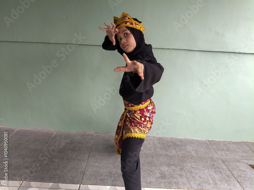 a girl is doing Pencak Silat martial arts moves by holding a machete. she is wearing a batik costume for performance. Pencak Silat is a traditional Indonesian martial art photo