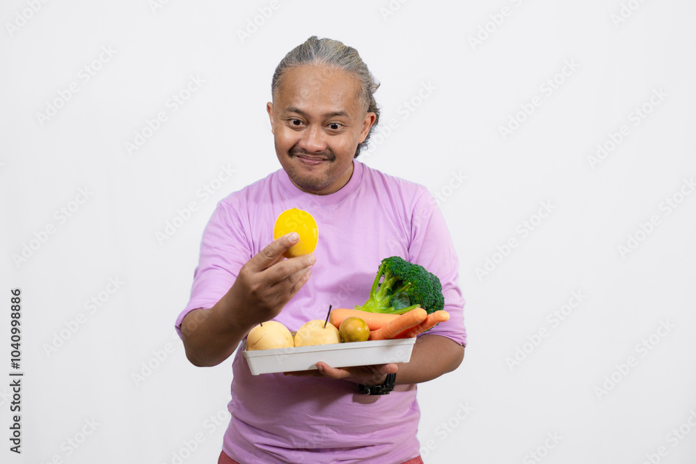 happy and energetic curly-haired Asian adult male standing with a tray full of fresh vegetables while showing a lemon, healthy lifestyle concept, isolated white background.
happy and energetic curly-haired Asian adult male standing with a tray full of fresh vegetables while showing a lemon, healthy lifestyle concept, isolated white background.