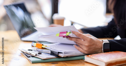 Business asian woman Reviewing Documents, business woman's hands meticulously reviewing a stack of documents, highlighting the details and precision of her work. 
 photo