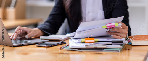Business asian woman Reviewing Documents, business woman's hands meticulously reviewing a stack of documents, highlighting the details and precision of her work. 
