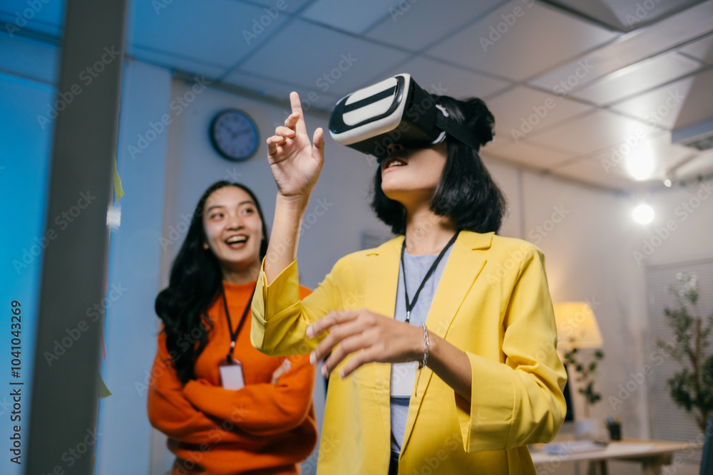Businesswoman is using a vr headset and interacting with virtual reality while her colleague is smiling and watching her Businesswoman is using a vr headset and interacting with virtual reality while her colleague is smiling and watching her