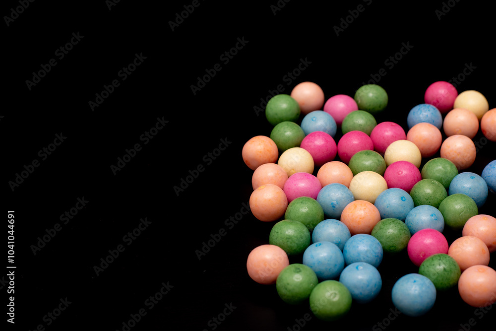 Bunch of colorful candy balls are spread out on a black background Bunch of colorful candy balls are spread out on a black background