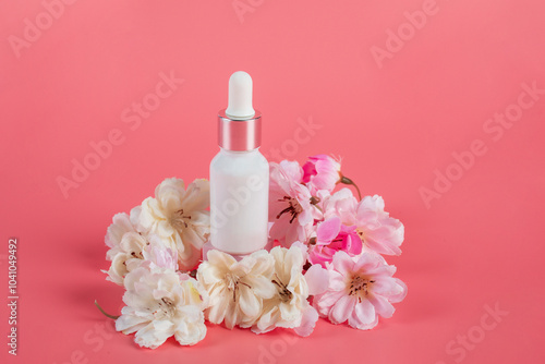 Plastic white tube for cream or lotion. Skin care or sunscreen cosmetic with fake flowers on pink background.