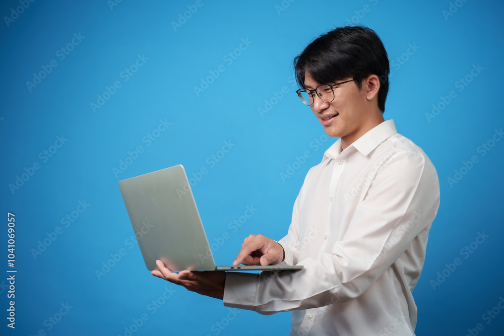 Male business man using laptop with blue background. Male business man using laptop with blue background.