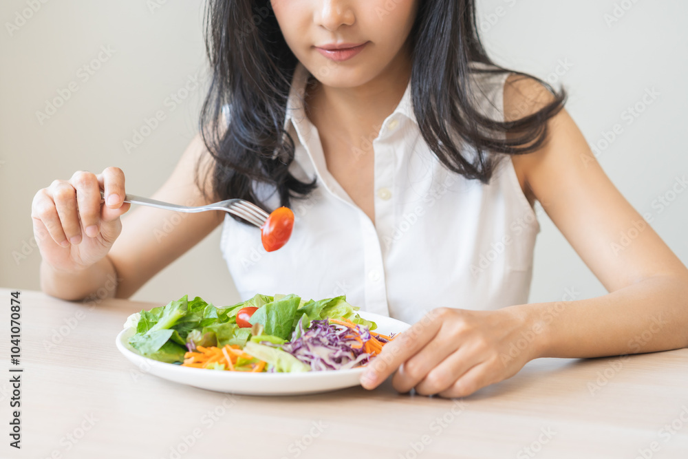 Diet in bored face, unhappy beautiful asian young woman, girl on dieting, holding fork at tomato on salad plate, dislike or tired with eat fresh vegetables. Nutrition of clean, healthy food good taste Diet in bored face, unhappy beautiful asian young woman, girl on dieting, holding fork at tomato on salad plate, dislike or tired with eat fresh vegetables. Nutrition of clean, healthy food good taste