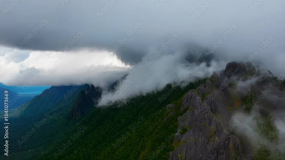 Mist-covered mountains are seen under a dark, stormy sky, creating a mystical and dramatic atmosphere. Mist-covered mountains are seen under a dark, stormy sky, creating a mystical and dramatic atmosphere.