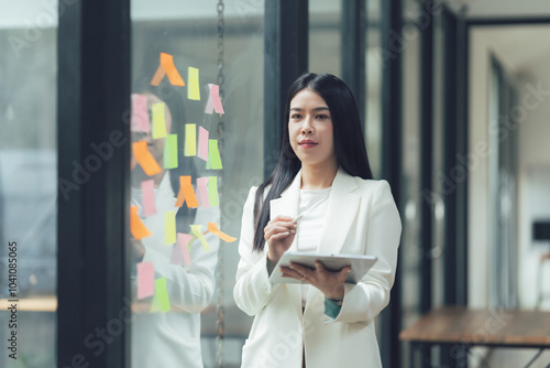 Strategic Thinking: A focused businesswoman contemplates ideas on sticky notes, her tablet in hand, as she plans the next steps in her project. Free Download Strategic Thinking: A focused businesswoman contemplates ideas on sticky notes, her tablet in hand, as she plans the next steps in her project. - GFXLoad