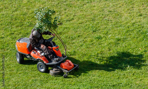 A person operating a lawn mower in a park, cutting the grass.