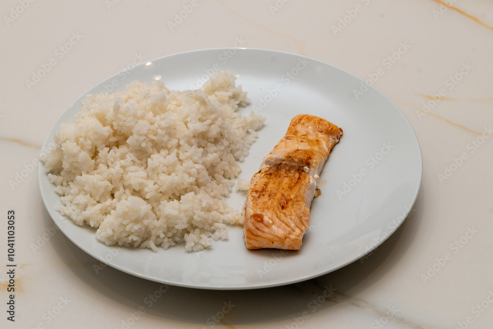 a white ceramic plate with a grilled salmon fillet and cooked rice on a white marbled table a white ceramic plate with a grilled salmon fillet and cooked rice on a white marbled table