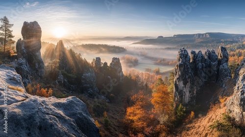 A panoramic view of a valley with rock formations and fog at sunrise.
