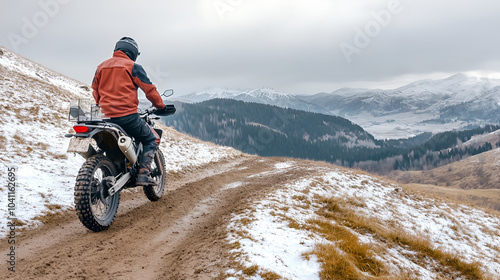 Motorcyclist braving cold overcast weather on mountainous dirt roads embodying extreme sport and active lifestyle in enduro off road touring photo