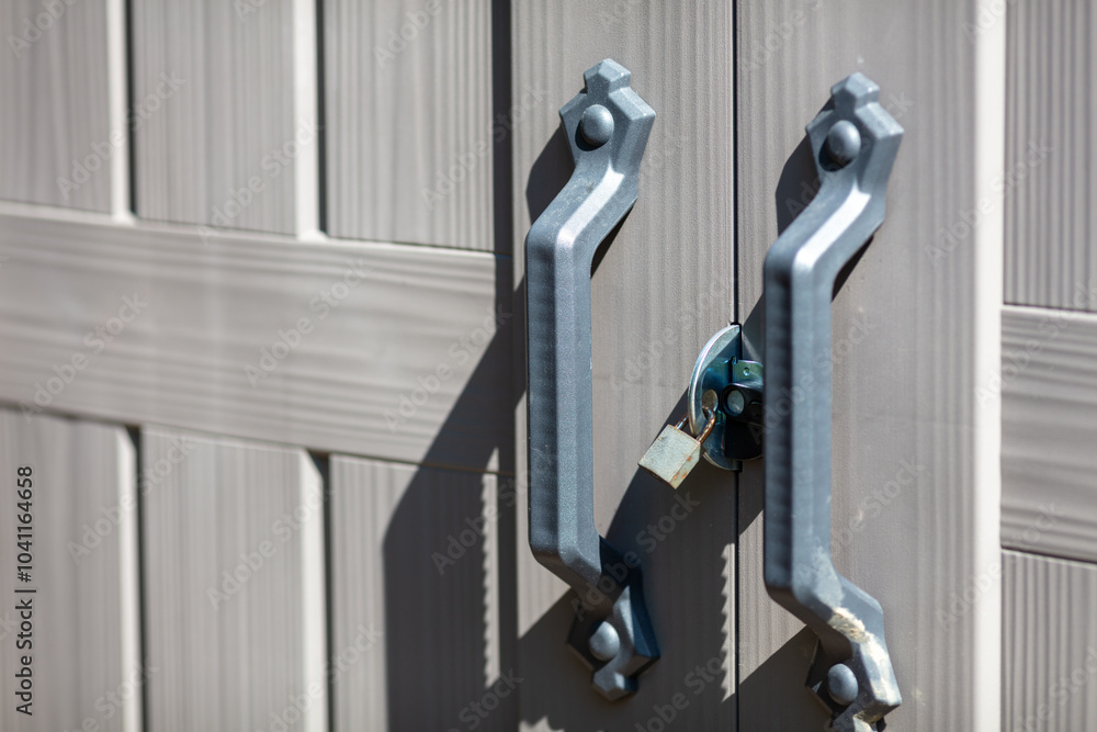 Close-Up of Double Door Handles and Lock on Grey Metal Gate in Sunlight, Symbolizing Security and Protection Close-Up of Double Door Handles and Lock on Grey Metal Gate in Sunlight, Symbolizing Security and Protection