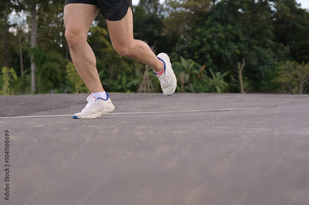 Low angle shot sportsman legs in sport shoes jogging along a paved road. Fitness and active lifestyle Low angle shot sportsman legs in sport shoes jogging along a paved road. Fitness and active lifestyle