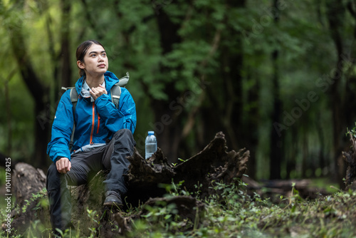 Foto Young Woman Resting in Forest During Outdoor Adventure, Wearing Blue Jacket, Sit