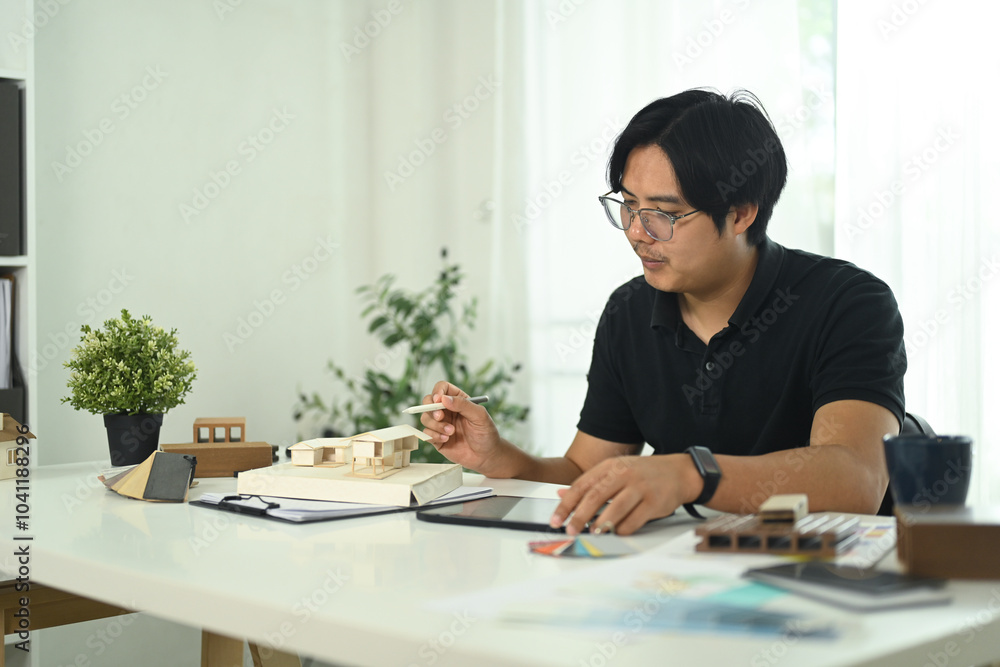 Architect working on a miniature house model in modern office office Architect working on a miniature house model in modern office office
