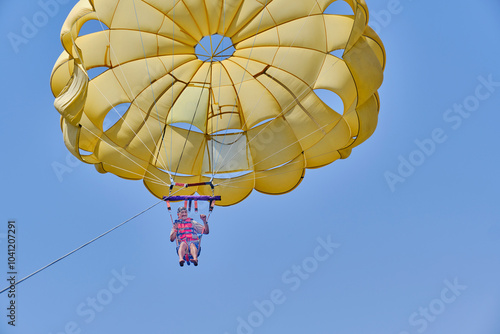 Senior asian man under dome of parachute enjoying parasailing against blue sky. photo