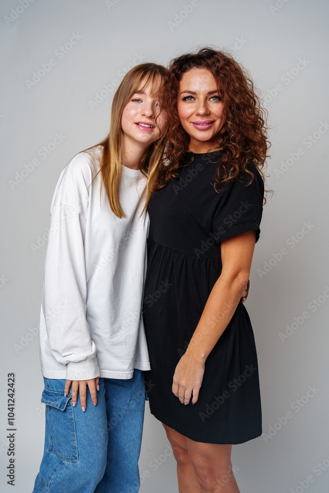 Two women standing together, one in white and the other in black, showcasing a warm connection Two women standing together, one in white and the other in black, showcasing a warm connection