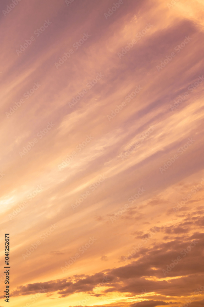 Obraz premium Sky with soft and fluffy pastel orange pink and blue colored clouds. Sunset background. Nature. sunrise. Vertical